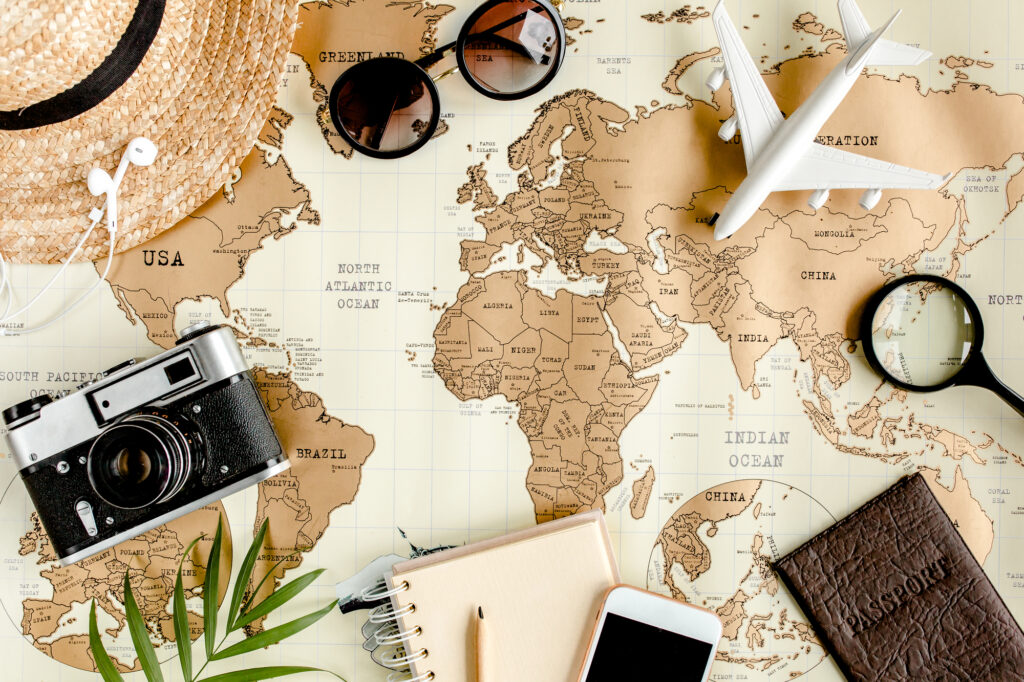 Planning vacation, travel plan, trip vacation using world map along with other travel accessories. Top view, flat lay. Travel, vacation concept.