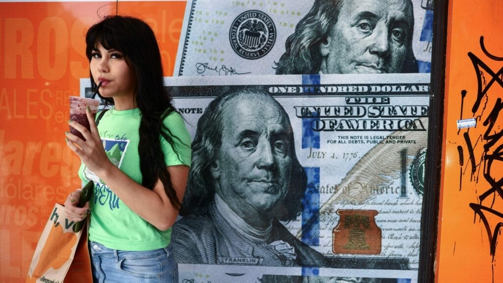 A woman drinks juice next to a currency exchange with United States Dollar bills printed on its windows  in Buenos Aires, Argentina, December 12, 2023. REUTERS/Tomas Cuesta
