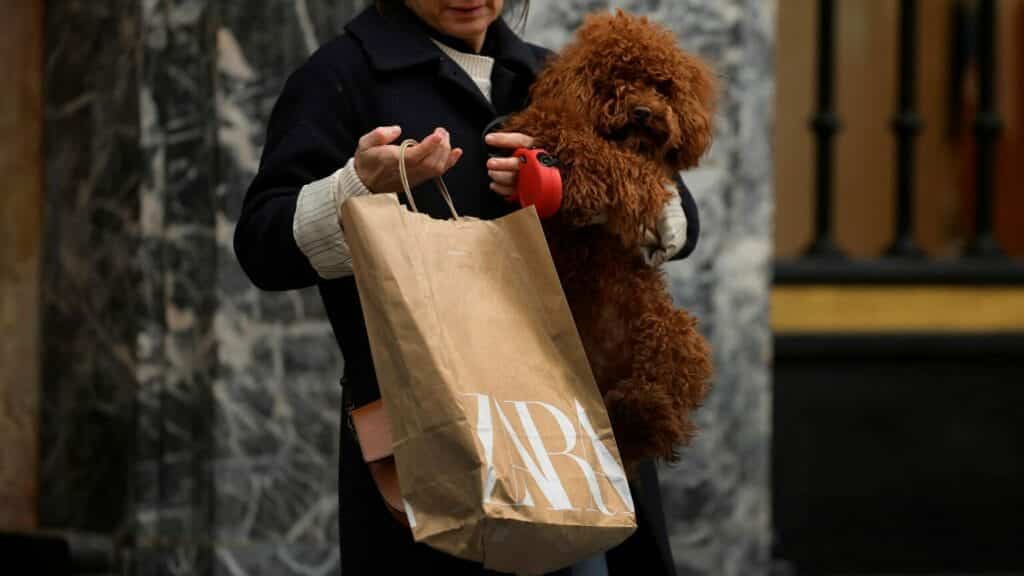 A woman carries a bag from Spanish multinational retail clothing chain Zara, while holding her dog, in the Gran Via of Bilbao, Spain, December 11, 2023. REUTERS/Vincent West