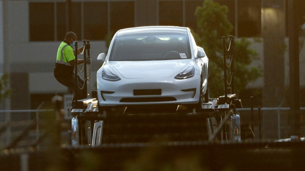 FILE PHOTO: A worker descends from the top deck of a car carrier trailer carrying Tesla electric vehicles at Tesla's primary vehicle factory in Fremont, California, U.S. May 11, 2020. REUTERS/Stephen Lam/File Photo