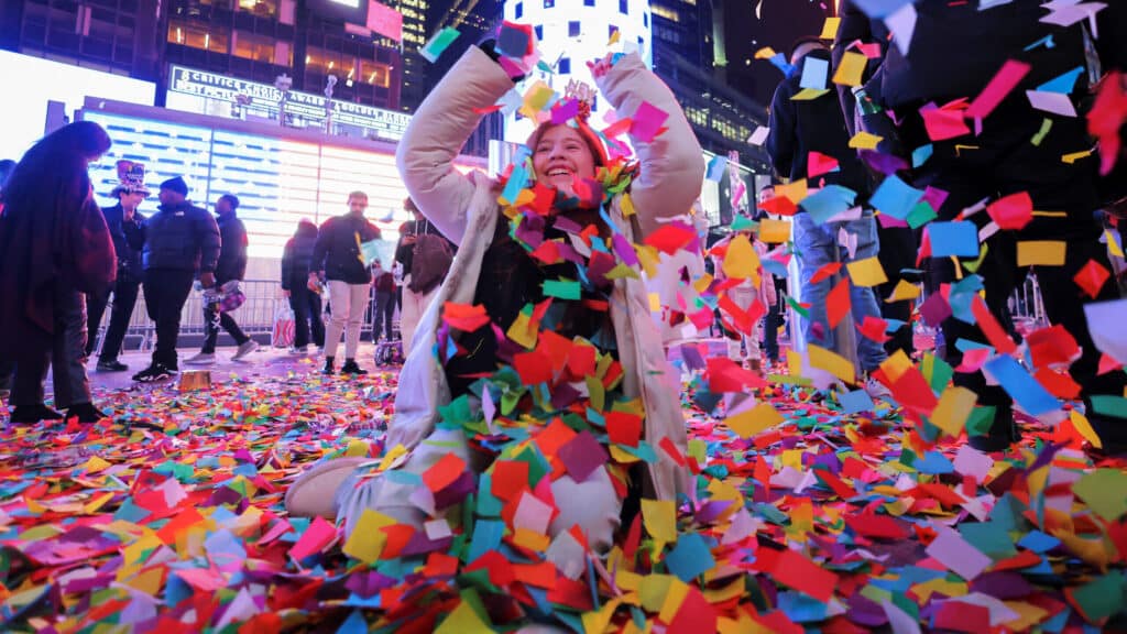 A reveller plays with confetti after the clock strikes midnight during New Year celebrations at Times Square, in New York City, New York, U.S., January 1, 2024. REUTERS/Andrew Kelly