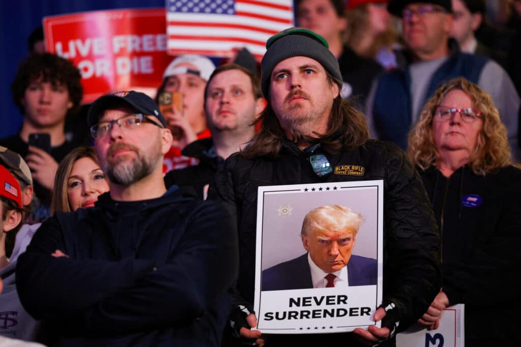 FILE PHOTO: A person holds a placard with the mugshot of Republican presidential candidate and former U.S. President Donald Trump, on the day of Trump's rally in Durham, New Hampshire, U.S. December 16, 2023. REUTERS/Brian Snyder/File Photo