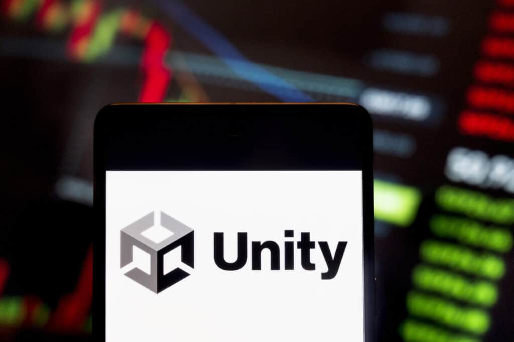 In this photo illustration, the American video game software development company, Unity Technologies (NYSE: U), logo seen displayed on a smartphone with an economic stock exchange index graph in the background.