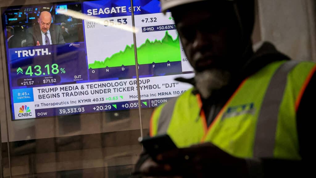FILE PHOTO: A man looks at this phone as a screen displays trading information about shares of Truth Social and Trump Media &amp; Technology Group, outside the Nasdaq Market site in New York City, U.S., March 26, 2024.  REUTERS/Brendan McDermid/File Photo