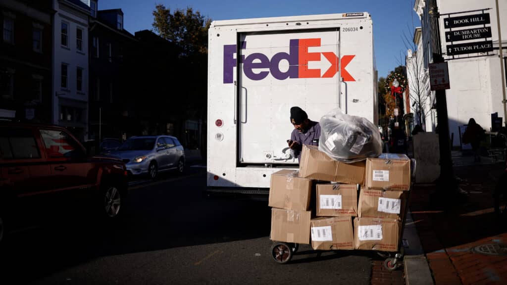 A driver of FedEx stands with packages near a delivery truck during Black Friday preparations in the Georgetown neighborhood of Washington, U.S., November 26, 2024. REUTERS/Benoit Tessier