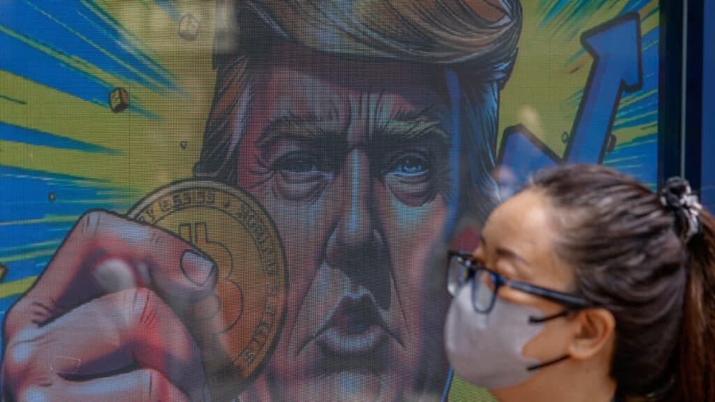 An illustration featuring U.S. President-elect Donald Trump holding Bitcoin is displayed outside a cryptocurrency exchange store after Bitcoin soars above $100,000, in Hong Kong, China, December 5, 2024. REUTERS/Tyrone Siu
