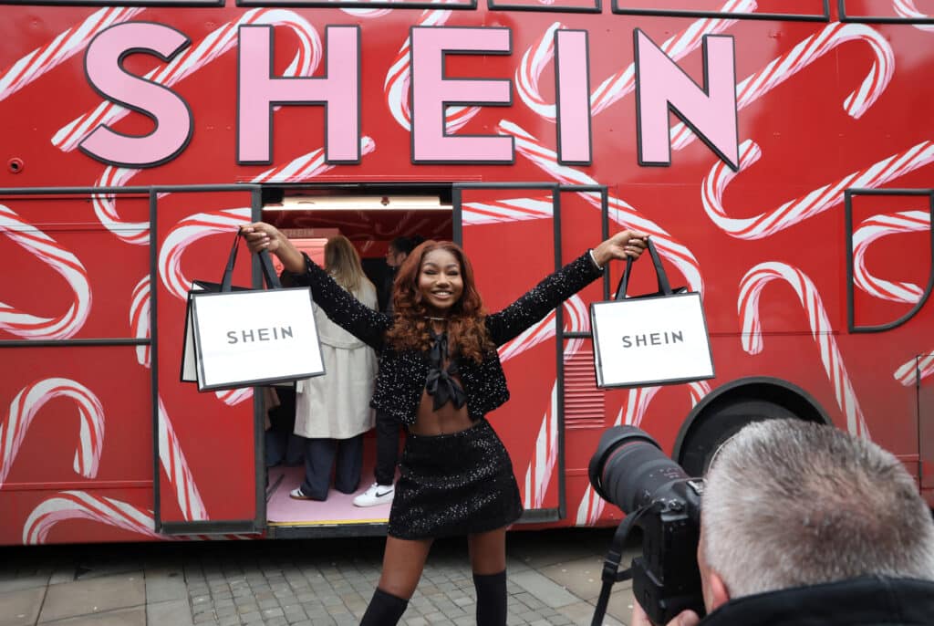 A shopper poses with bags of promotional merchandise as she visits fashion retailer Shein's Christmas bus tour, in Manchester, Britain, December 13, 2024. REUTERS/Temilade Adelaja