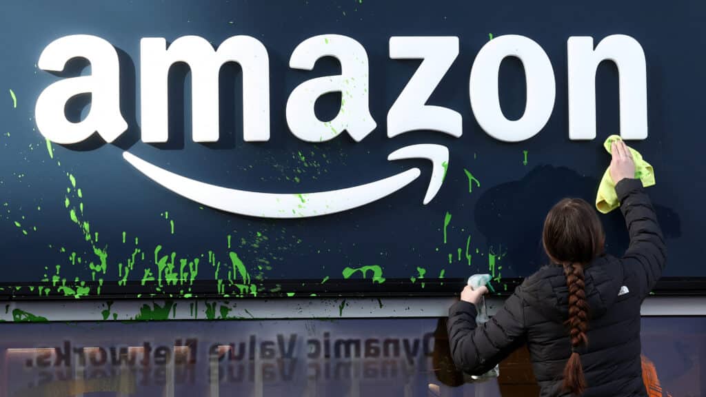 A woman cleans the storewindow of the Amazon house after activists sprayed paint its facade during a protest on the opening day of the 55th annual meeting of the World Economic Forum (WEF) in Davos, Switzerland, January 20, 2025. REUTERS/Yves Herman