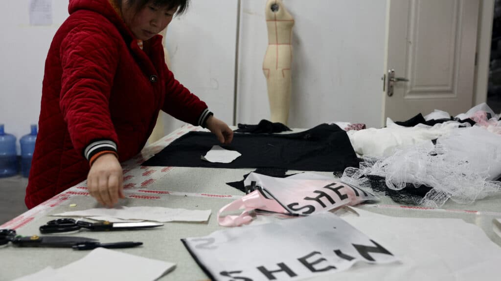 FILE PHOTO: An employee prepares to cut a fabric next to Shein packaging at the Midnight Charm Garment lingerie factory in Guanyun county of Lianyungang, Jiangsu province, China November 25, 2024. REUTERS/Florence Lo/File Photo