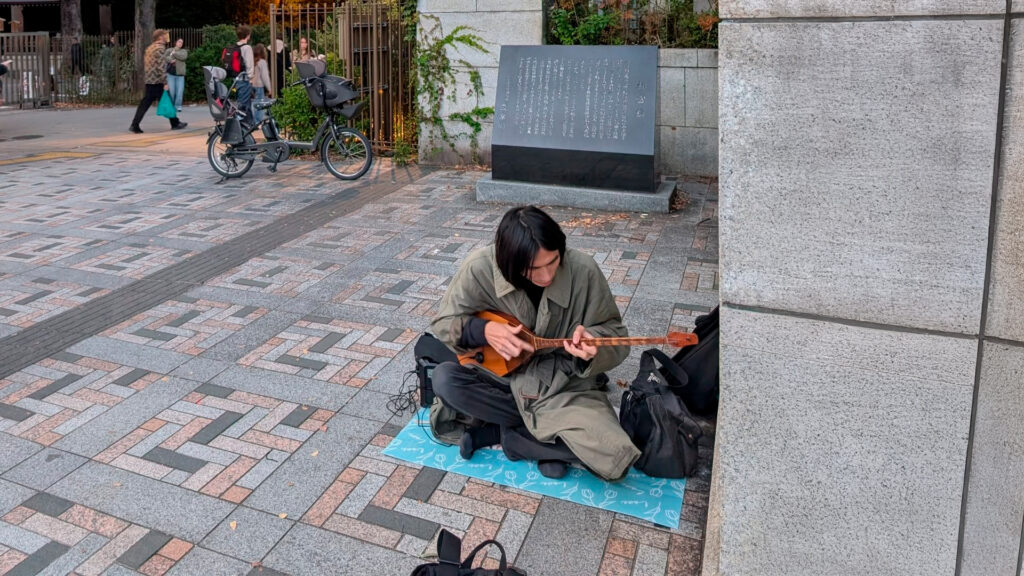 Японский уличный музыкант играет на домбре в Токио