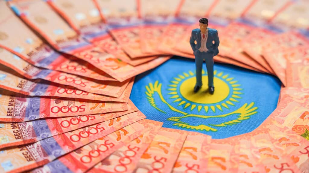 The figure of a businessman stands on the Kazakh flag among tenge banknotes. Small business. The director of the company