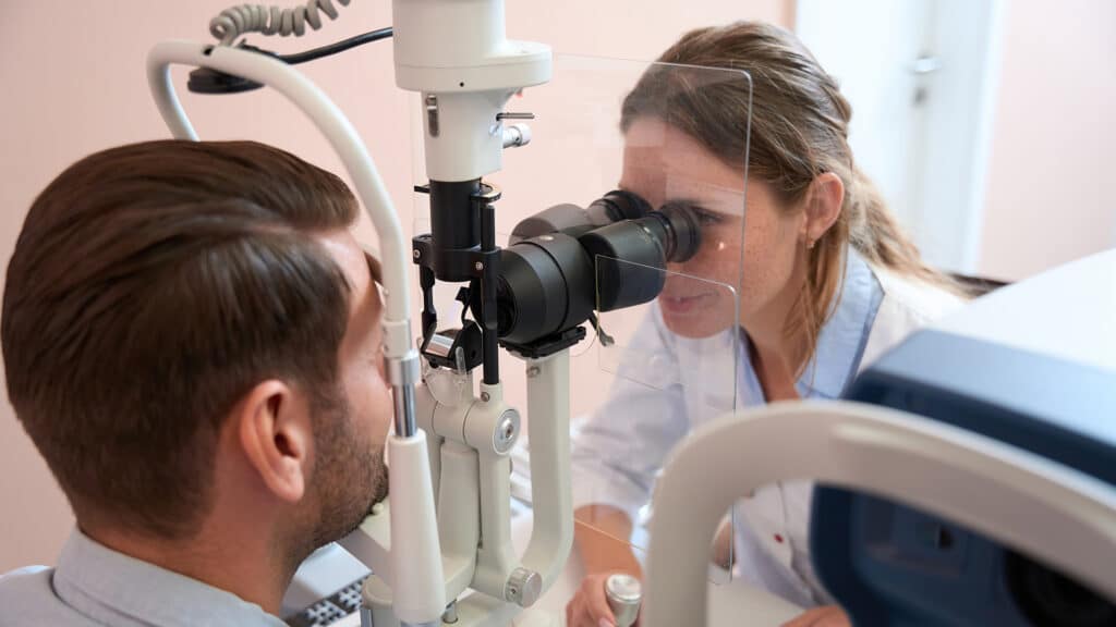 Qualified female ophthalmologist is diagnostics vision of man in optician center