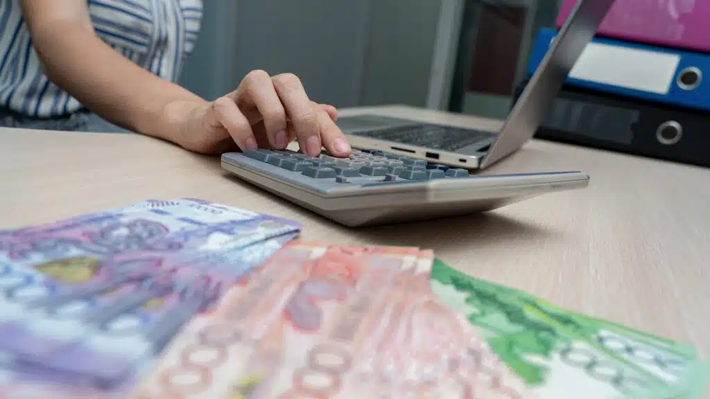 Almaty, Almaty Region, Kazakhstan. 
September 12 2025 Person calculating money on a calculator while working on a laptop.
