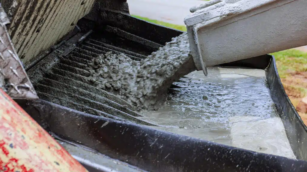 Worker pours fresh concrete into mixer at home construction site during works constructed day