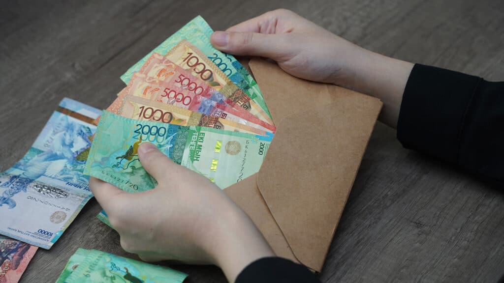 An envelope with money of different denominations of Kazakhstani tenge in the hands of a person