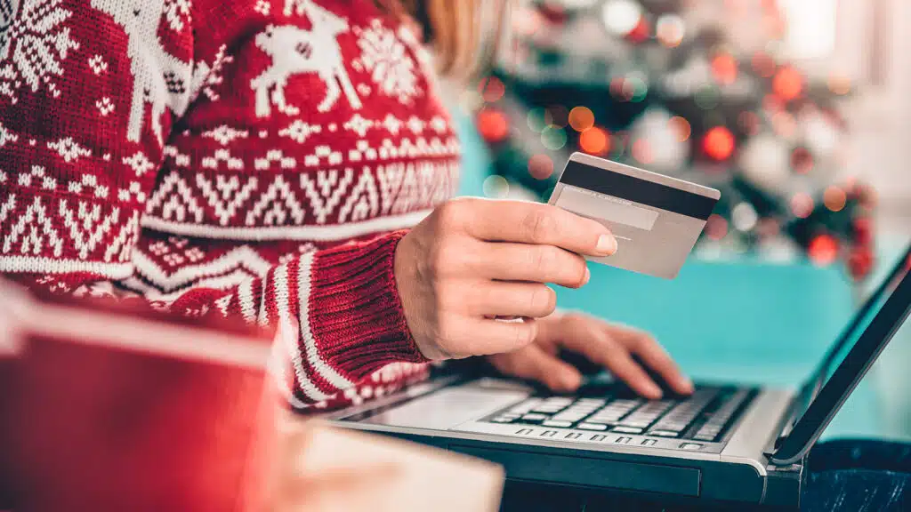 Women wearing red sweater sitting on the sofa and using laptop and credit card to shopping online at home