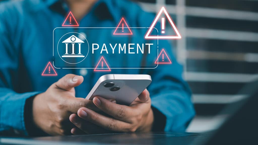 Online payment fraud warning during mobile transaction as man uses smartphone for digital banking, facing potential fraud, phishing, and cybersecurity threats in financial transactions.