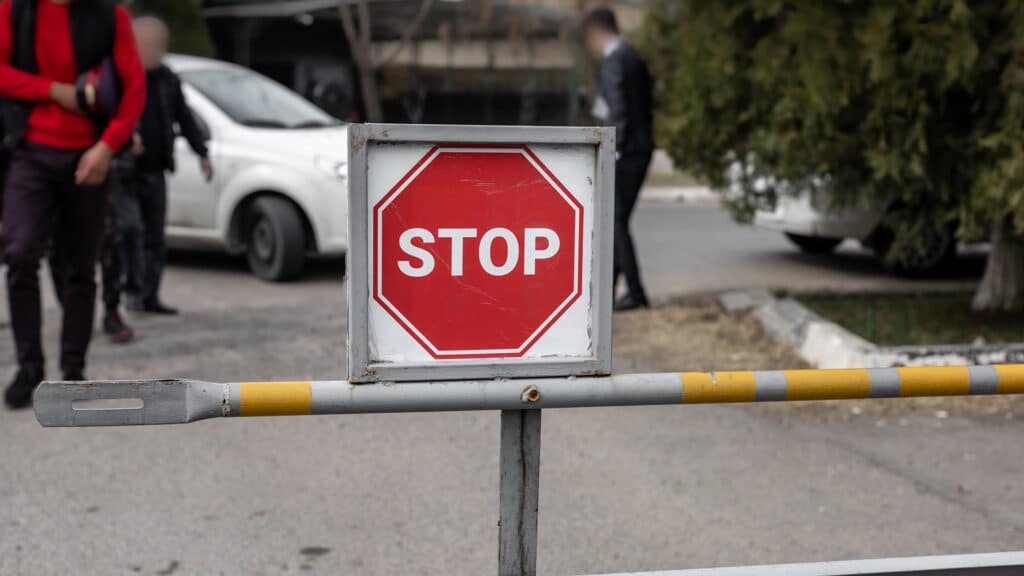 Tashkent, Uzbekistan - 03.03.2023 : Border crossing barrier with the sign "STOP" on the border with a car and people