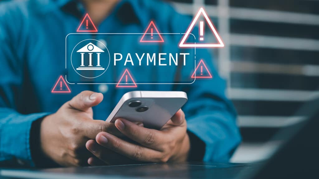 Online payment fraud warning during mobile transaction as man uses smartphone for digital banking, facing potential fraud, phishing, and cybersecurity threats in financial transactions.