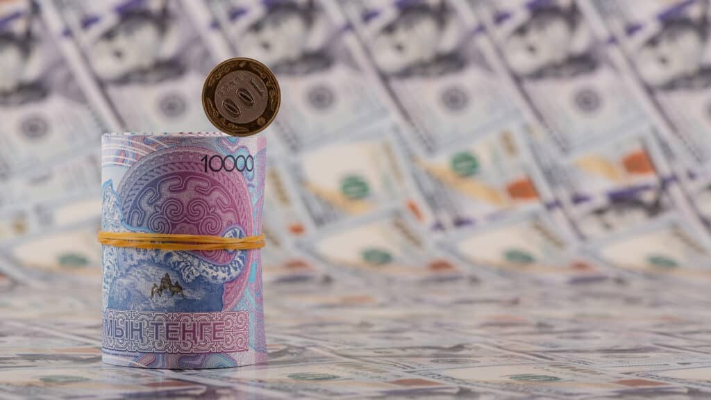 A conceptual plot about inflation in Kazakhstan featuring 10,000 tenge bills, a 100 tenge coin, and 100 US dollar bills.